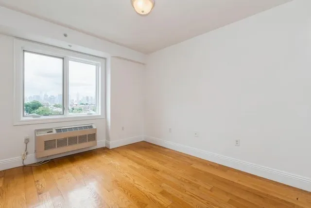 a view of an empty room with a window and wooden floor