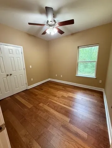 an empty room with wooden floor fan and windows