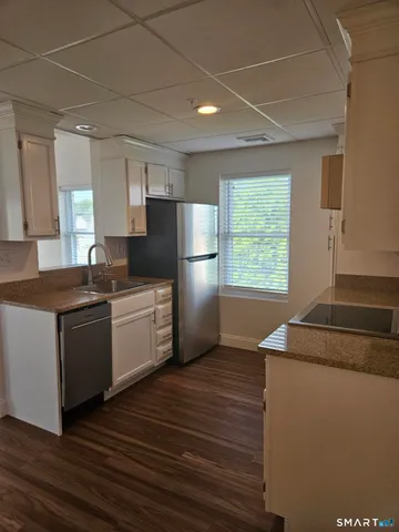 a kitchen with granite countertop a refrigerator and a stove top oven