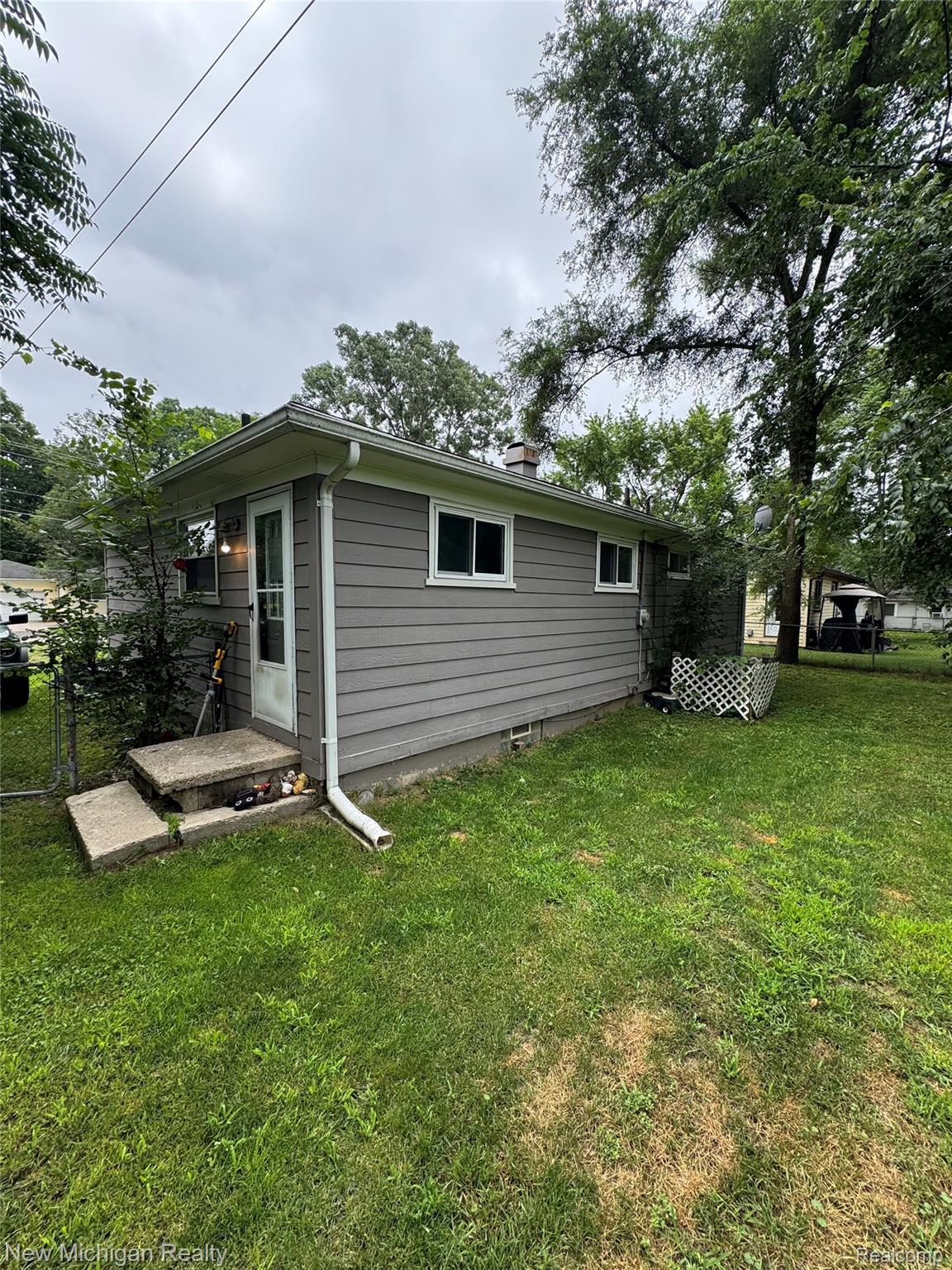 870 Farnsworth Road White Lake, MI 48386 - Photo 3 of 20 Gray horizontal siding exterior with white window trim and a white storm door