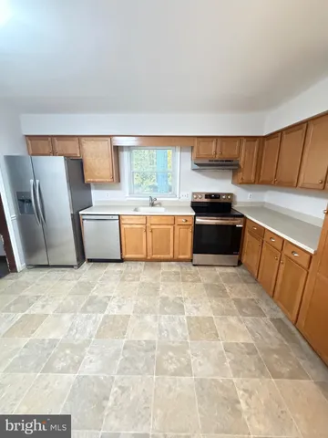 a large kitchen with a stove a sink dishwasher and a refrigerator