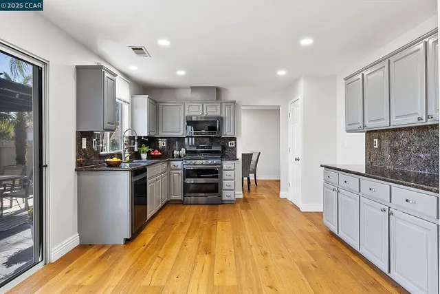 a kitchen with granite countertop a refrigerator stove top oven and sink