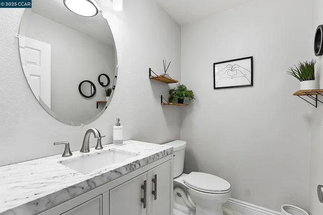 a bathroom with a granite countertop toilet sink and mirror