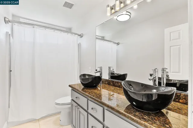 a bathroom with a granite countertop sink a toilet and a mirror