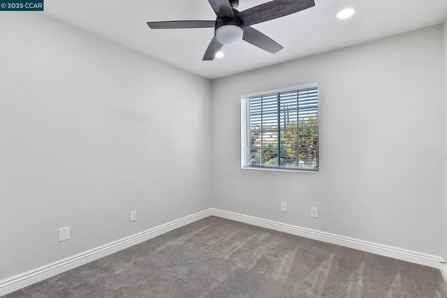an empty room with ceiling fan and window