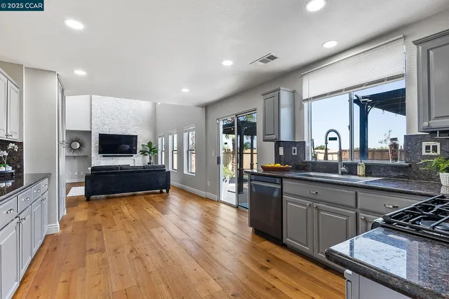a large kitchen with stainless steel appliances granite countertop a stove and a wooden floors