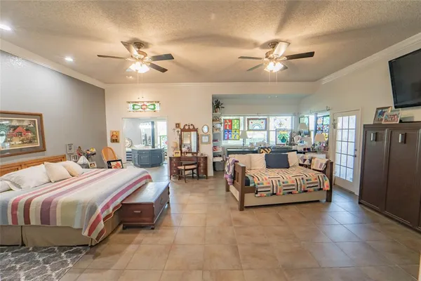 a bedroom with a bed a chandelier furniture and a flat screen tv