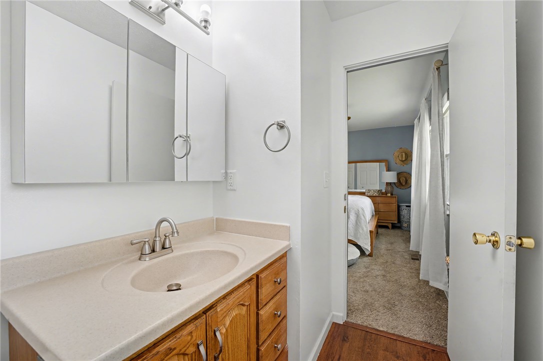 4919 Silver Arrow Drive Riverside, OH 45424 - Photo 33 of 57 This bright bathroom features a single vanity, a wall-mounted mirror, and an adjacent bedroom with carpeted flooring.