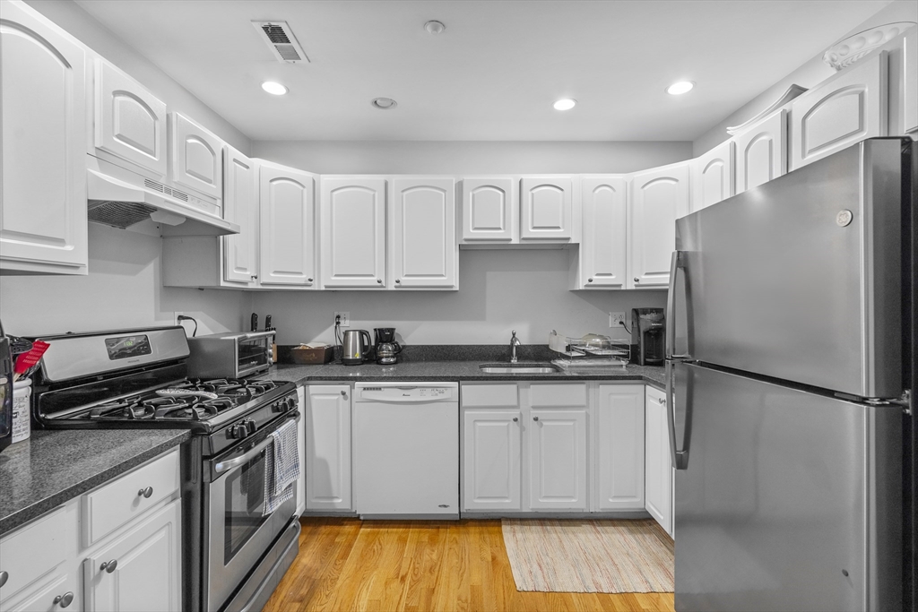 a kitchen with stainless steel appliances granite countertop a sink stove and refrigerator