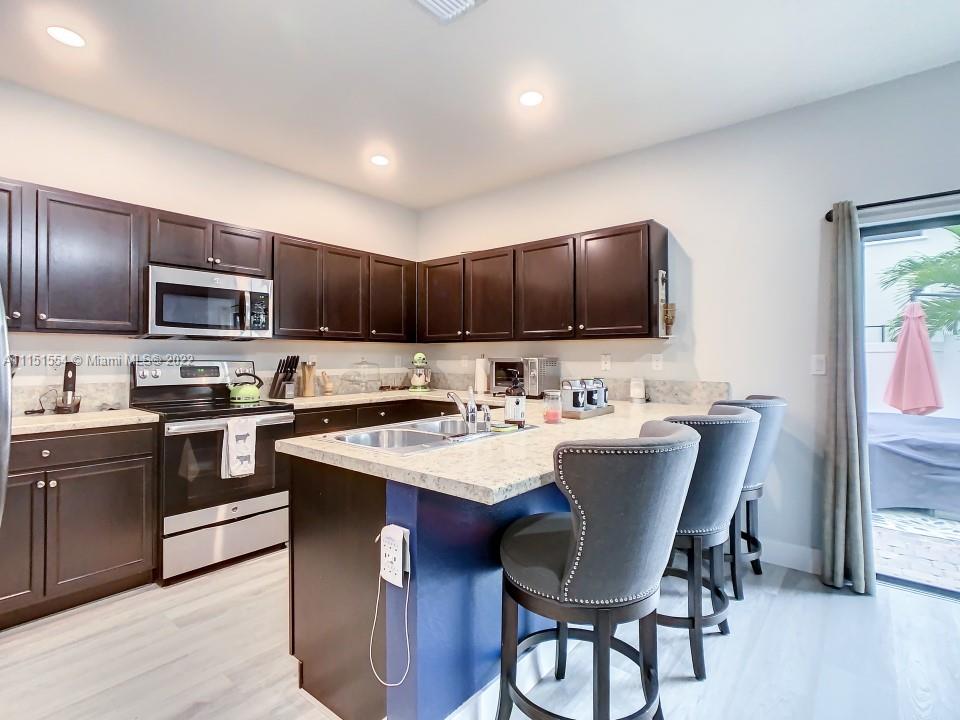 9326 West 33rd Lane Hialeah, FL 33018 - Photo 7 of 52 a kitchen with kitchen island granite countertop a sink counter and chairs