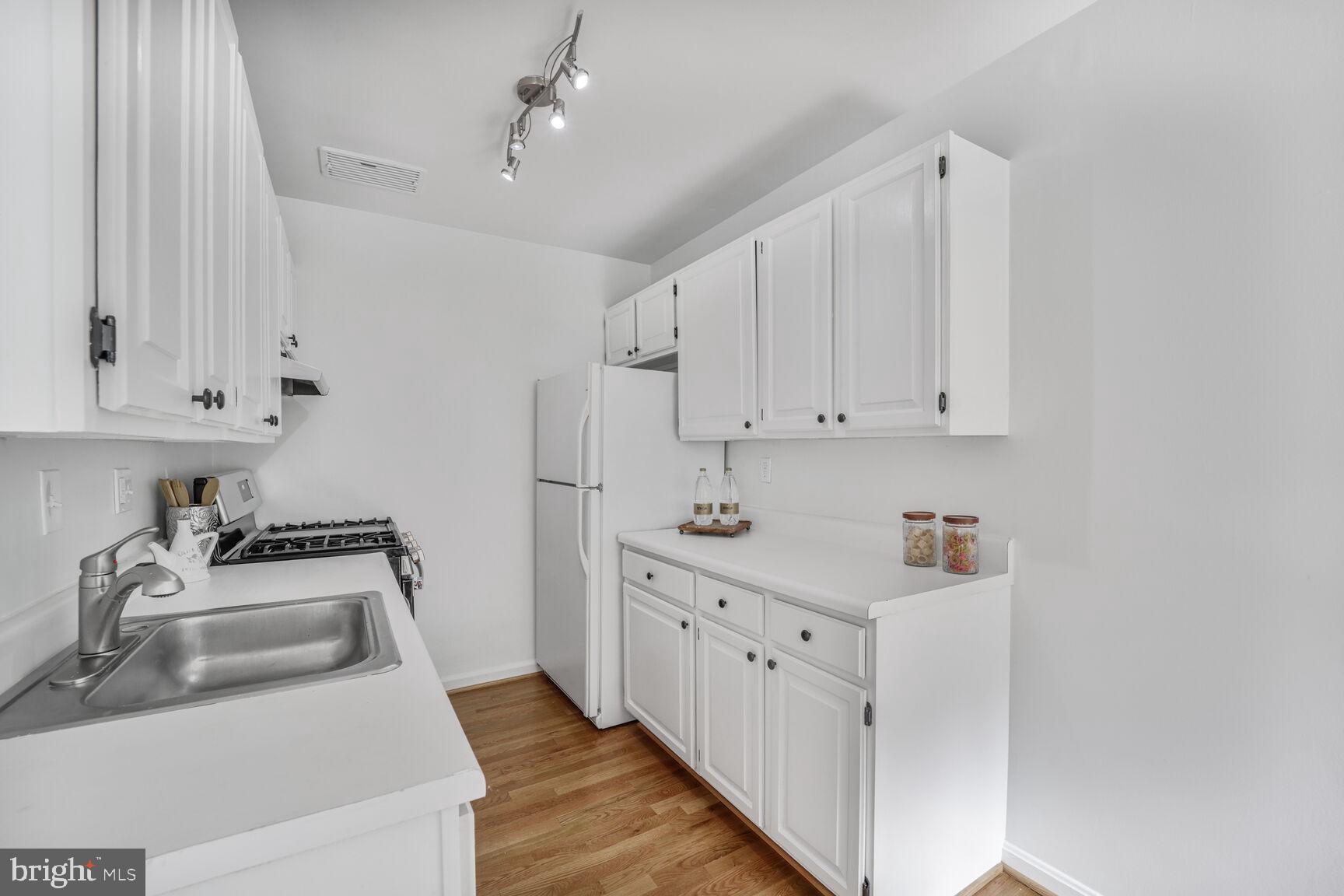 4114 Davis Place Northwest, Unit 311 Washington, DC 20007 - Photo 6 of 37 a kitchen with white cabinets sink and stove