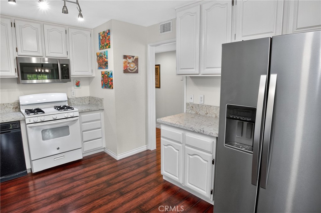 1083 Lakeview Terrace Azusa, CA 91702 - Photo 21 of 36 a kitchen with stainless steel appliances white cabinets and wooden floor