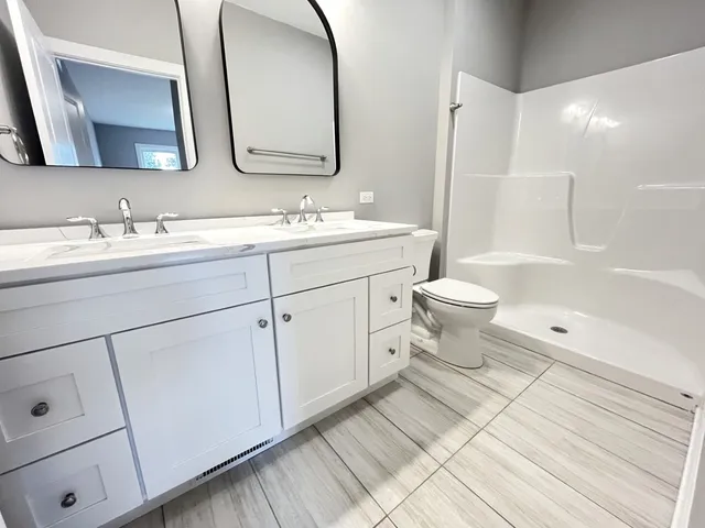a bathroom with a double vanity sink a toilet and a mirror
