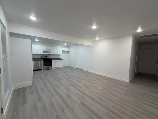 an empty room with wooden floor and a sink
