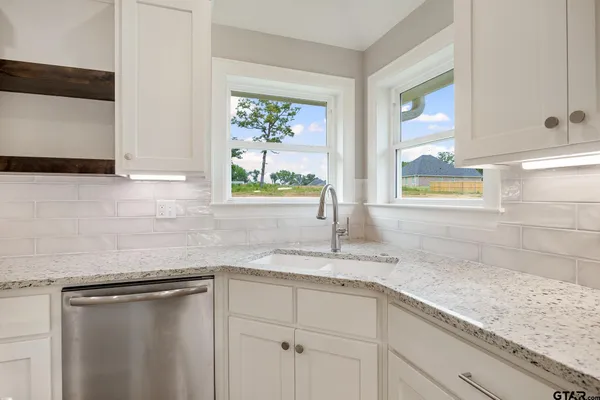 a kitchen with granite countertop stainless steel appliances a sink window and cabinets
