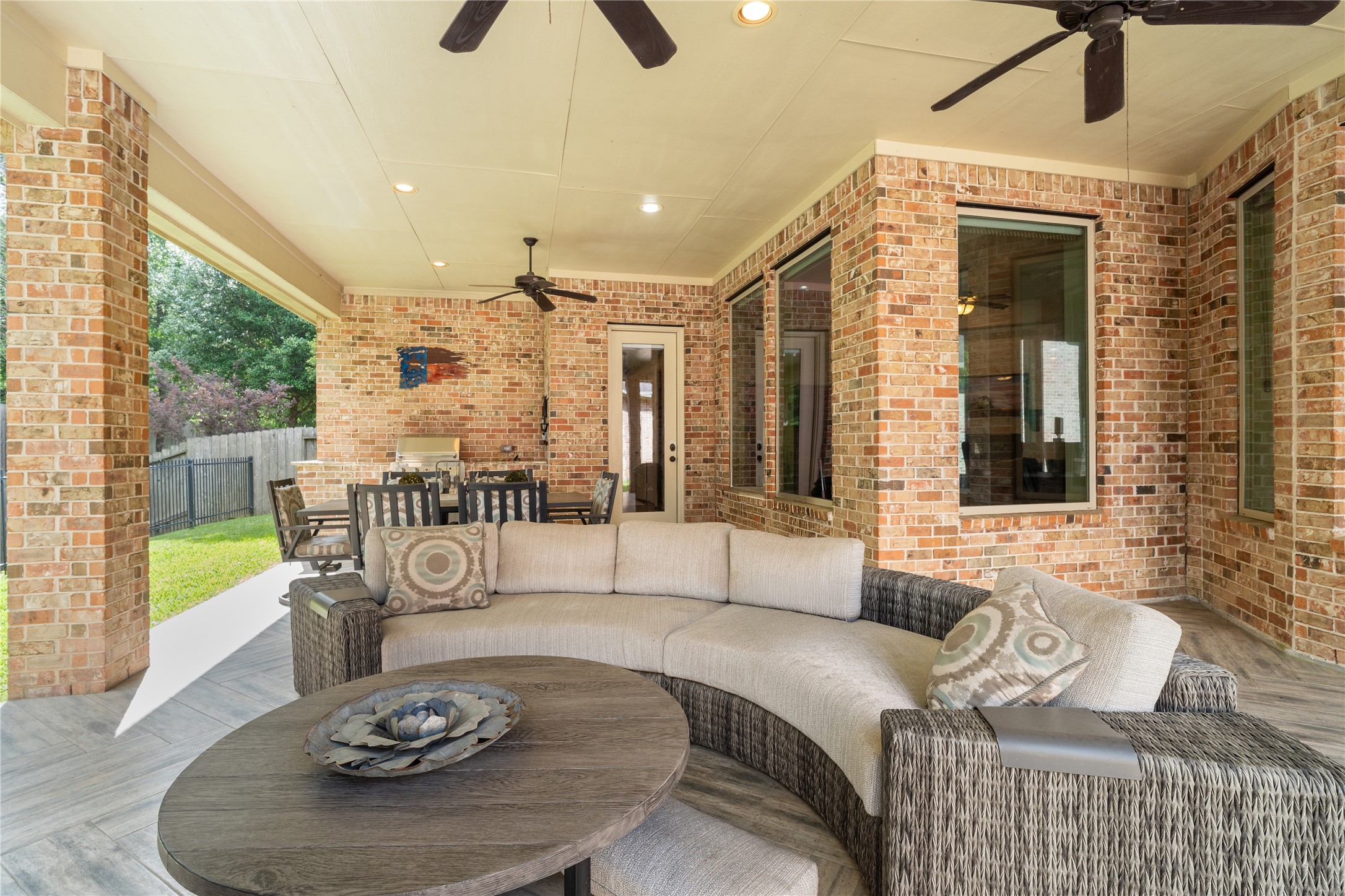 19813 Cullen Ridge Drive Porter, TX 77365 - Photo 40 of 44 Experience the perfect blend of comfort and elegance in this inviting outdoor living space, featuring a cozy seating area and dining set under a stylish covered patio with ceiling fans, ideal for entertaining or relaxing year-round.