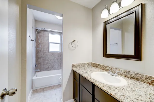 a bathroom with a granite countertop sink and mirror with bathtub
