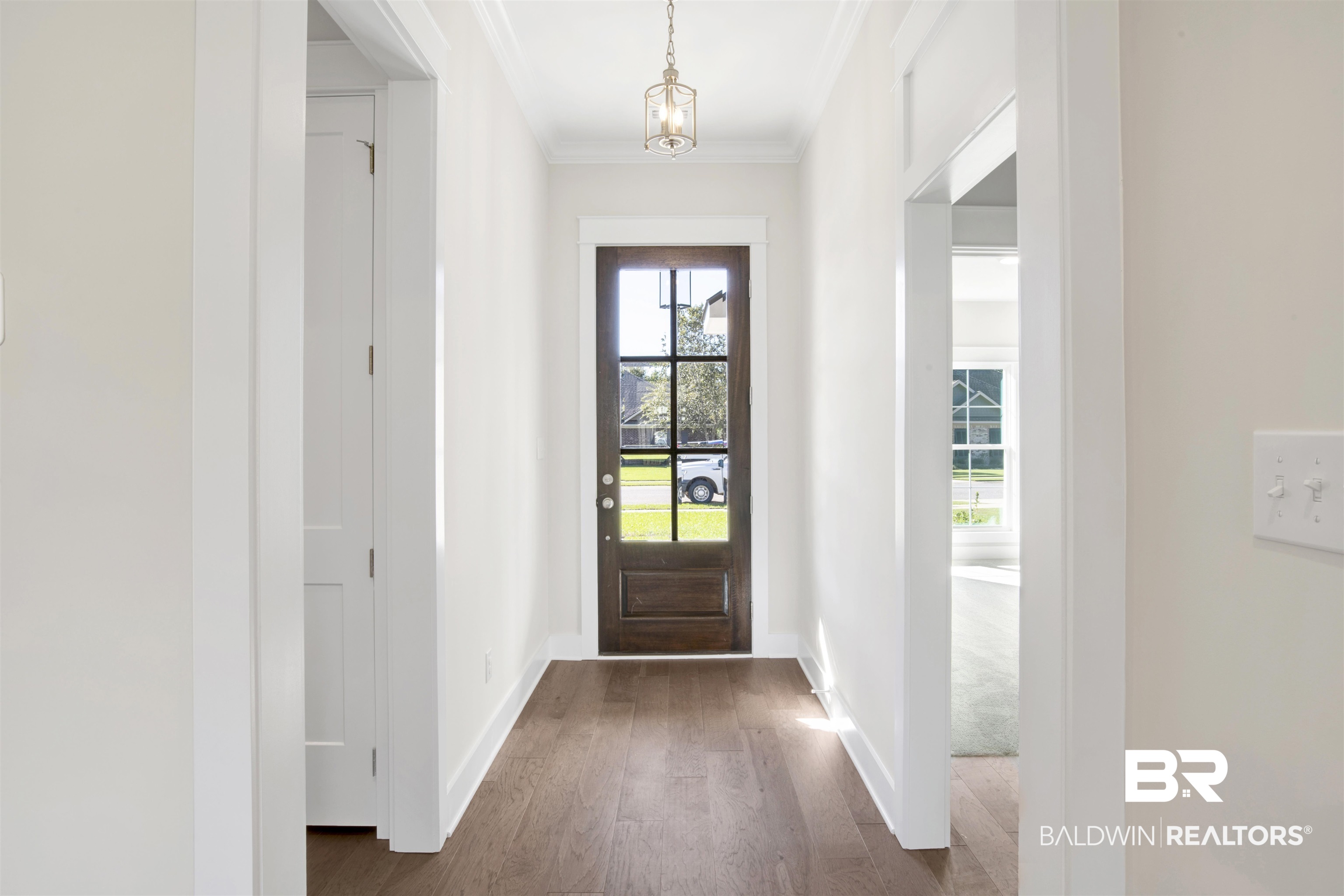 9687 Widgeon Court Daphne, AL 36526 - Photo 4 of 40 Doorway to outside featuring dark hardwood / wood-style floors, crown molding, and an inviting chandelier