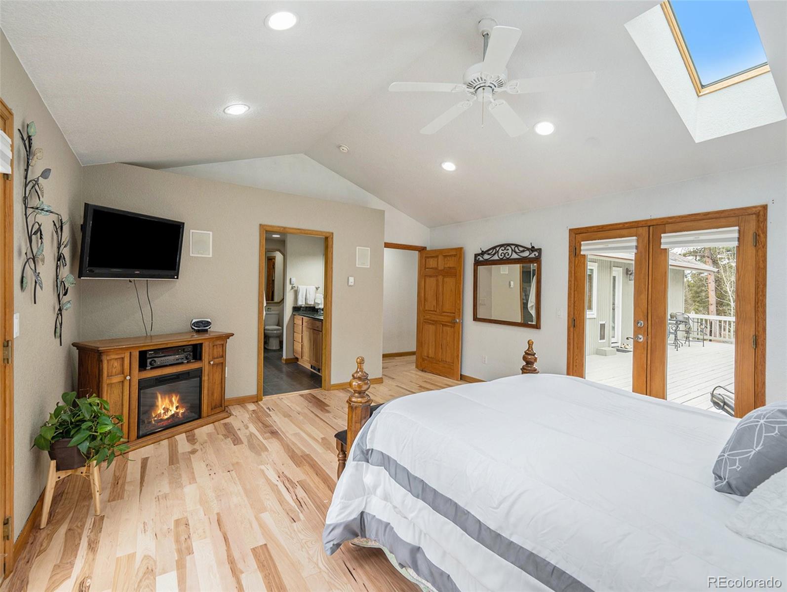 11748 Apache Trail Conifer, CO 80433 - Photo 12 of 34 a spacious bedroom with a large bed and a flat screen tv