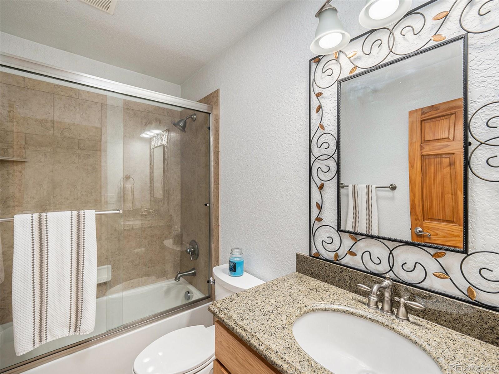 11748 Apache Trail Conifer, CO 80433 - Photo 17 of 34 a bathroom with a granite countertop sink mirror toilet and bathtub