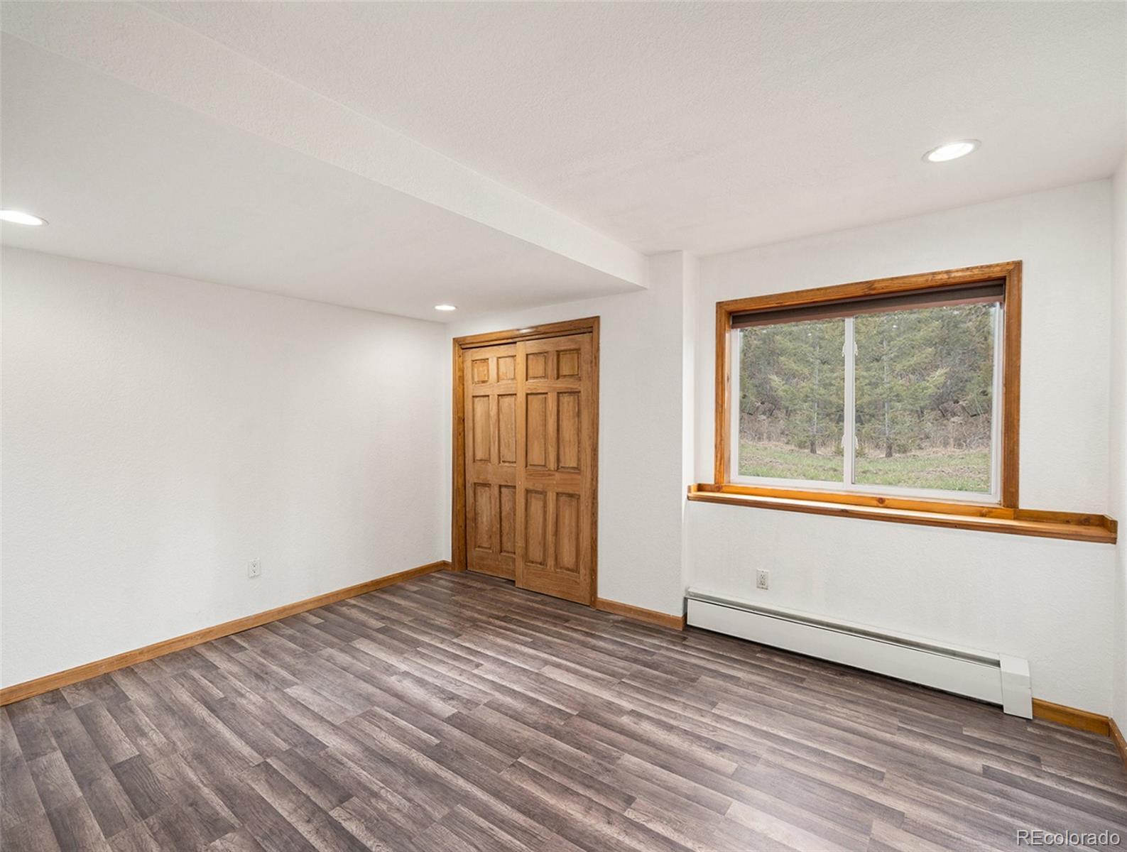 11748 Apache Trail Conifer, CO 80433 - Photo 25 of 34 an empty room with wooden floor and windows