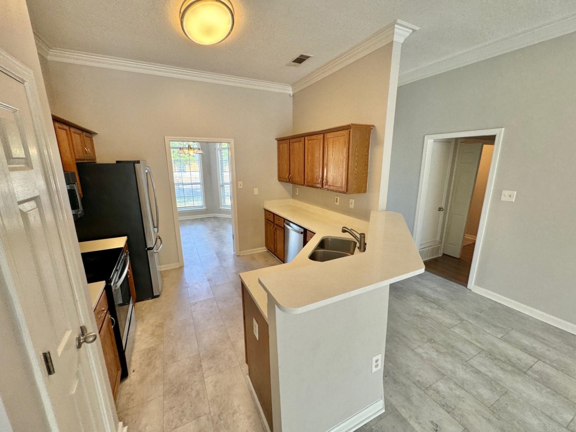 779 North Sanga Road Memphis, TN 38018 - Photo 3 of 12 Kitchen featuring a textured ceiling, sink, kitchen peninsula, appliances with stainless steel finishes, and crown molding