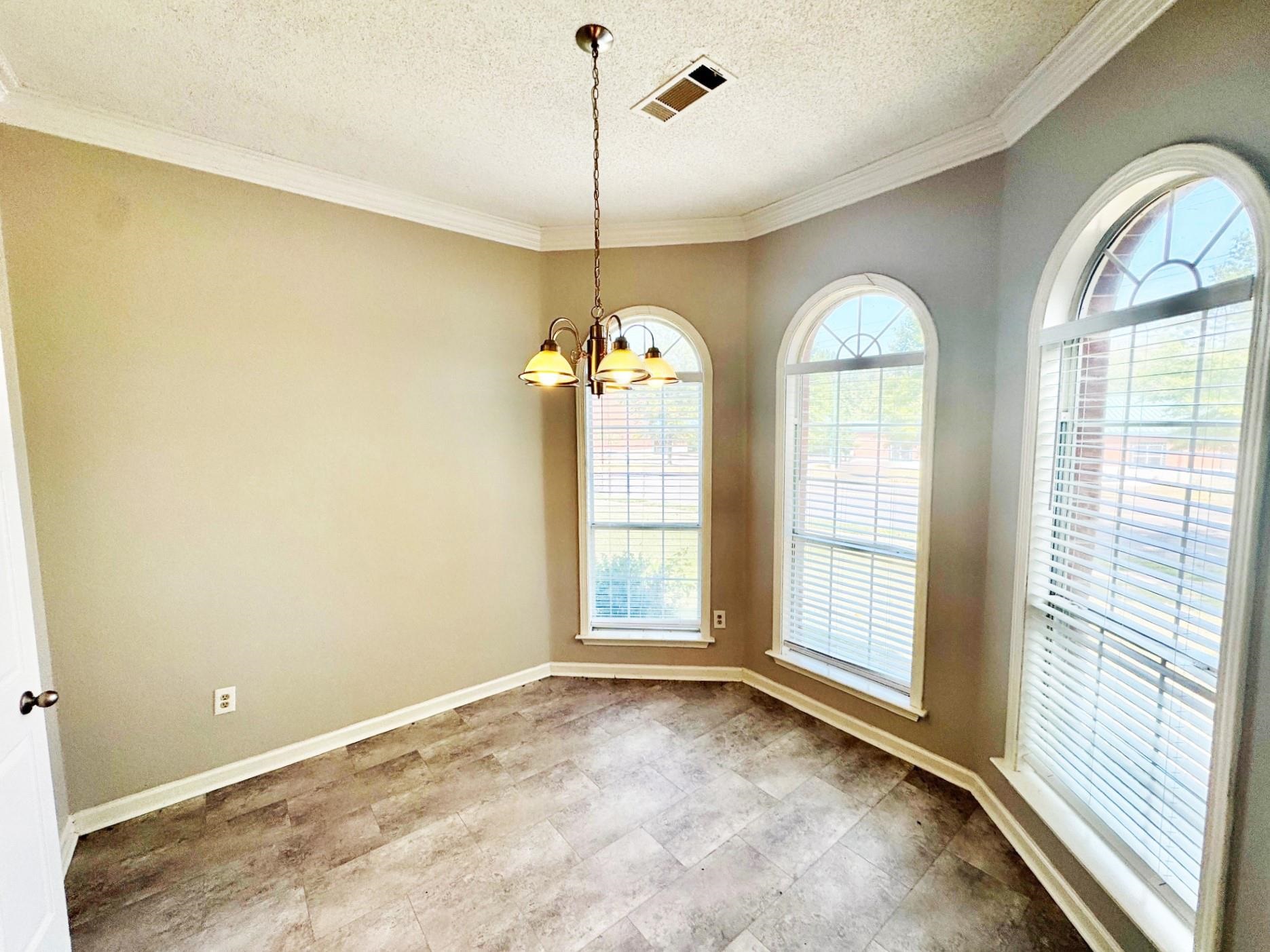779 North Sanga Road Memphis, TN 38018 - Photo 4 of 12 Spare room with a textured ceiling, ornamental molding, and a notable chandelier