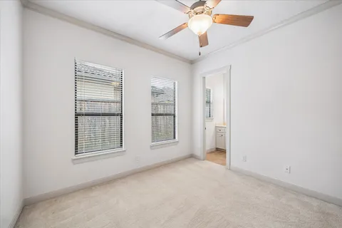 an empty room with chandelier fan and windows