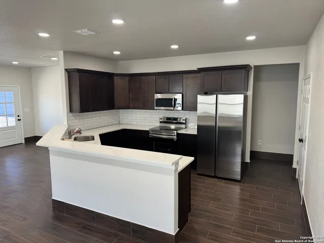 a kitchen with kitchen island stainless steel appliances a sink and a refrigerator