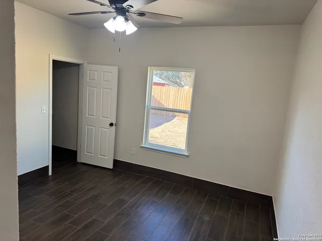 a view of an empty room with wooden floor and a window