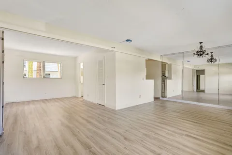 a view of an empty room with window and wooden floor
