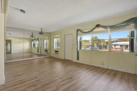 a view of an empty room with window and wooden floor