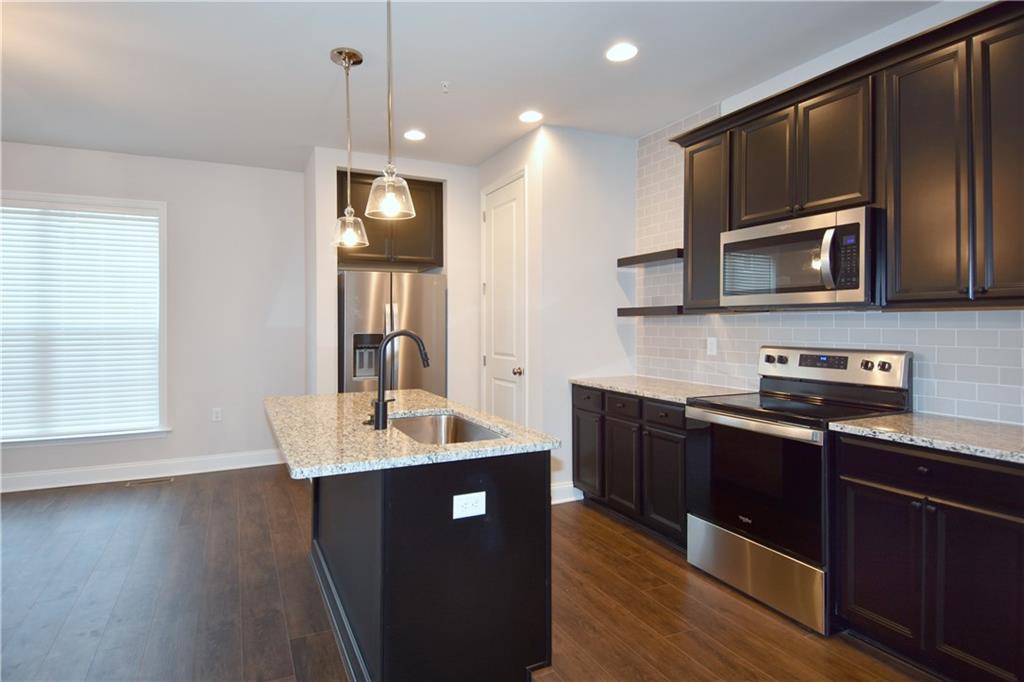 122 Gress Road Cranberry Township, PA 16066 - Photo 18 of 33 a kitchen with stainless steel appliances kitchen island granite countertop a stove a sink dishwasher and a microwave oven with wooden floor