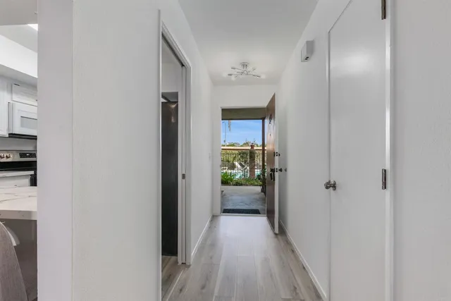 a view of a hallway with wooden floor and a bathroom