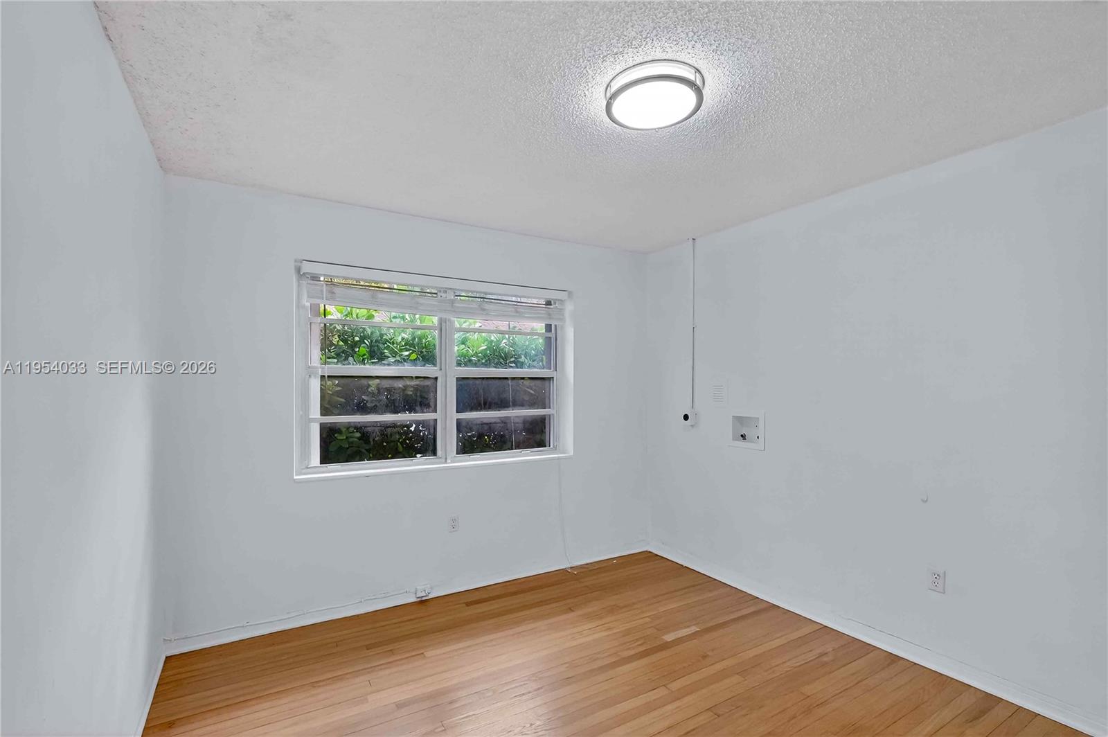 2399 Southwest 26th Lane Miami, FL 33133 - Photo 17 of 39 a view of an empty room with wooden floor and a window