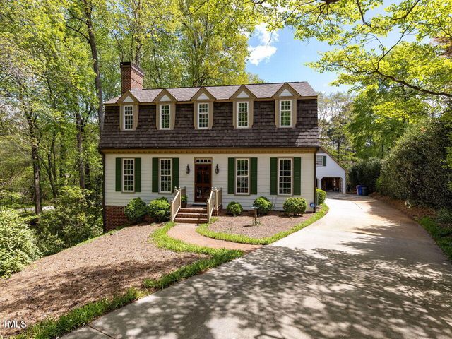 a view of a brick house with a yard and large trees