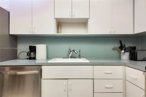 a kitchen with granite countertop white cabinets and a sink