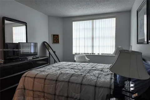 a bedroom with a bed a lamp and a flat tv screen
