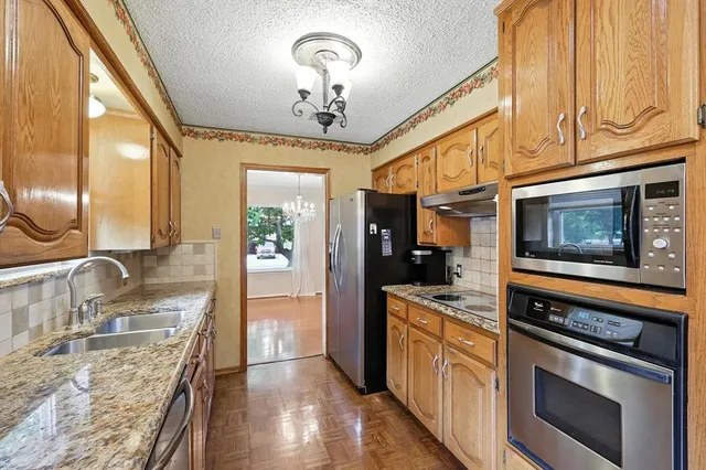 a kitchen with stainless steel appliances granite countertop a sink a stove cabinets and a dining table