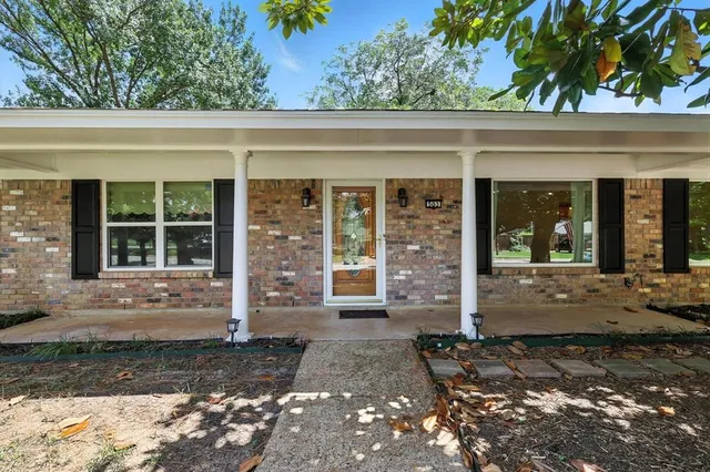 a front view of a house with a large window and plants