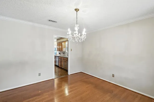 a view of an empty room with window and hardwood floor