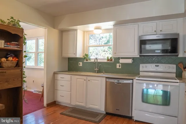 a kitchen with granite countertop a stove a sink and a microwave