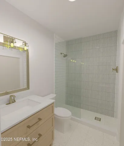 a bathroom with a granite countertop sink a toilet and shower