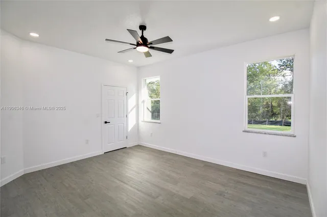 an empty room with windows and fan