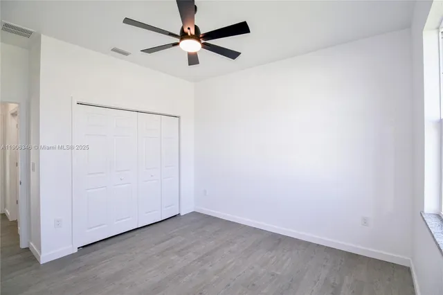 an empty room with a fan & a ceiling fan