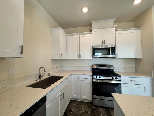 a kitchen with white cabinets a sink and appliances