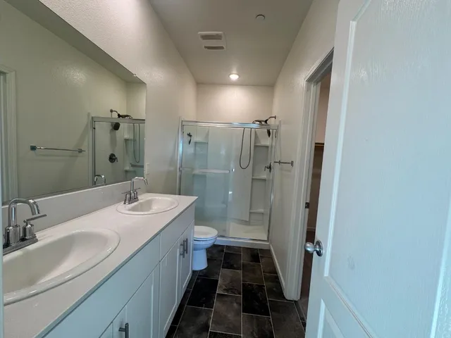 a bathroom with a double vanity sink toilet mirror and shower