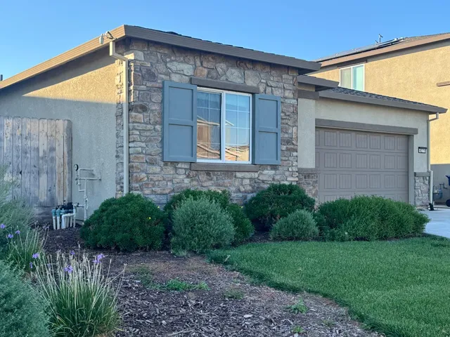 a view of a house with brick walls and a yard with plants