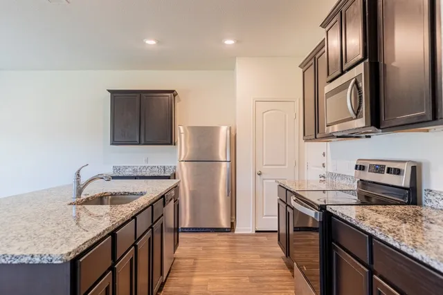 a kitchen with stainless steel appliances granite countertop a sink and wooden floor