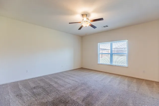 an empty room with windows and fan